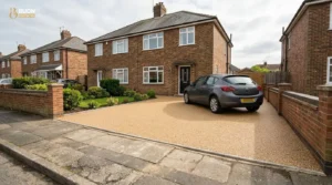 Newly installed resin bound driveway in natural gravel tones outside a UK semi-detached house